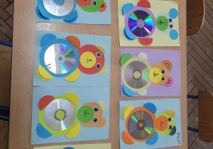 Na stoliku widać prace plastyczne wykonane przez dzieci - misie z papierowych kółek i płyt CD.