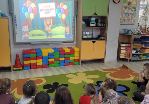 Przedszkolaki oglądają film edukacyjny na tablicy multimedialnej.