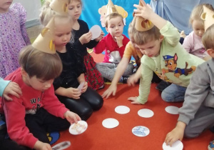 Dzieci siedzą na dywanie i grają w misiowe memory.