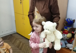 Emma trzyma białego misia ,którego wyjęła z torby. Obok stoi nauczyciel w stroju niedźwiedzia.