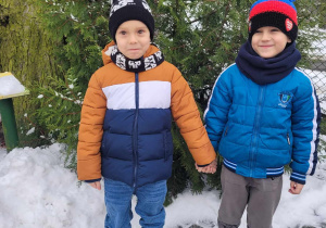 Antoś i Eryk stoją na śniegu trzymając się za ręce