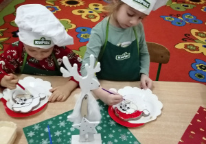 Amanda i Hubert podczas malowania lukrem ciasteczkowego Mikołaja.