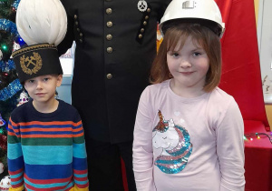 Samuel i Ala pozują do zdjęcia razem z zaproszonym do przedszkola górnikiem. Dziewczynka ma na głowie kask, a chłopiec czapkę górniczą.