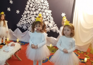 Emma i Nadia stoją przed dziećmi. W tle dekoracja i stojące dzieci.