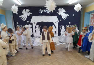 Franek stoi na środku sceny, a dzieci tańczą w kółeczkach przy pastorałce "Ach, co za noc". W tle dekoracja jasełkowa.