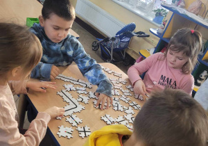 Gabryś i Alicja siedzą przy stoliku, na którym układają puzzle EduSense.