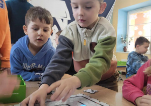 Julek układa puzzle Edusense, po których jeździ zaprogramowany Ozobot. Pracy chłopca przygląda się Karol.