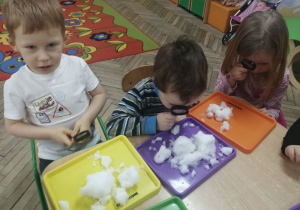 Bruno, Bartek i Nikola obserwują przez lupę płatki śniegu znajdujące się na tacy.
