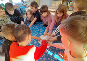 Dzieci stoją przy wspólnym stole i dotykają śniegu w misce.