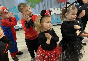 Dzieci z grupy "Pszczółek" tańczą obok siebie przy muzyce.