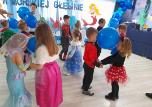 Dzieci podczas konkursu tańczą w parach trzymając balony między głowami.