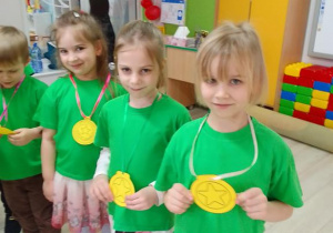 Witek, Lena, Zuzia i Ula w zielonych koszulkach prezentują medale.