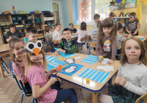 Dzieci z grupy Słoneczek siedzą przy stolikach w trakcie tworzenia pracy plastycznej