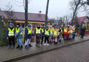 Dzieci ubrane w kamizelki odblaskowe idą do pobliskiego sklepu