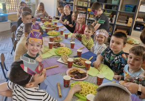 Dzieci z grupy "Słoneczek" siedzą przy wspólnym stole w trakcie słodkiego poczęstunku.