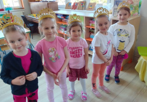 Grupa dziewczynek prezentuje się w złotych diademach.