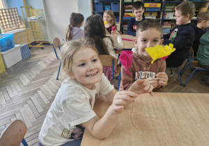 Anastazja i Julek pokazują wykonanie przez siebie kwiaty z bibuły.