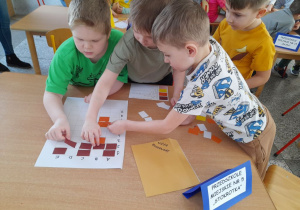 Karol, Arek, Filip i Eryk układają na planszy wieżę Roszpunki zapełniając pola kartonikami zgodnie z podanym kodem.