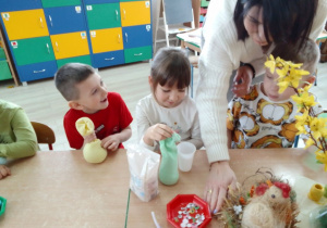Mikołaj, Natalka, Antek i Pani Ola napełniają skarpetki ryżem.
