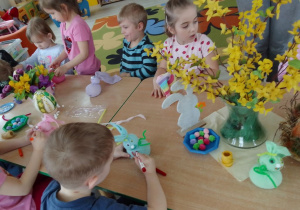 Dzieci przy stole podczas wykonywania wielkanocnego zajączka ze skarpetki.