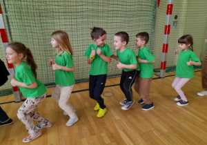 Sześcioro dzieci idzie jedno za drugim z kciukami podniesionymi do góry podczas zabawy integracyjnej - "Krasnoludek".