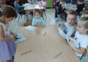 Dzieci wycinają nożyczkami kształt dłoni z niebieskiego papieru