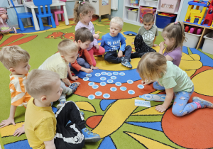 Maluchy podczas zabawy na dywanie, układają kropelki wody wg wzoru.