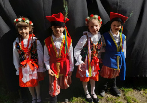 Czworo dzieci ubranych w stroje krakowskie stoi obok sceny w parku Traugutta.