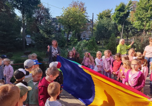 Zabawa z chustą, która pełniła rolę kurtyny. Po jednej stronie chusty stoją dziewczynki , po drugiej chłopcy. W tle Pani Agnieszka, która prowadziła zabawę z chustą.