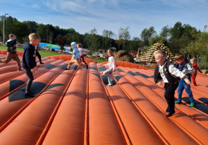 Grupka dzieci skacze na dyniowej trampolinie.