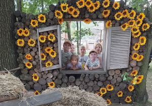 Sześcioro dzieci stoi w okienku ozdobionym kwiatami.