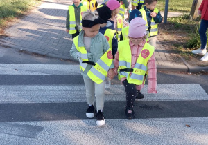 Dzieci przechodzą po pasach przez ulicę.