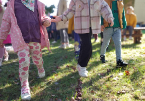 Nadia, Emma i Staś podążają za strzałką ułożoną z kasztanów.