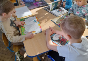 Grupka dzieci ogląda przy stole książki z bajkami.