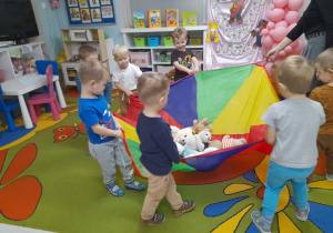 Dzieci chodzą przy muzyce trzymając chustę animacyjną, na której leżą misie.