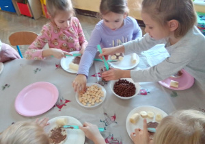 Grupa Słoneczek przy stolikach samodzielne przygotowuje "misiowe kanapki".