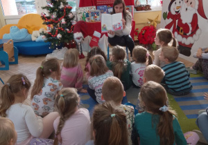 Mama Julii pokazuje dzieciom obrazek ilustrujący opowieść "Święty Mikołaj pociesza smoka".