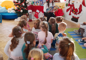 Mama Julii czyta kolejną książkę pt. "Idą święta" M. Zientali. W tle dekoracja świąteczna.