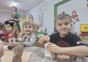 Oluś i Staś mieszają czekoladę w styropianowych kubeczkach.