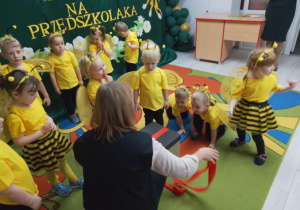 Pani Agnieszka z grupą dzieci rozpakowują prezent od rodziców.