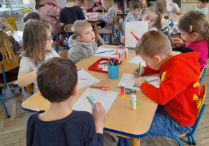 Dzieci siedzą przy stolikach i wypełniają kartę pracy - tworzą swoją szczoteczkę do zębów.