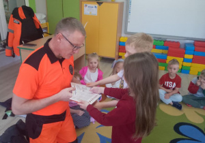 Amanda i Bruno wręczają ratownikowi podziękowanie i czekoladki.