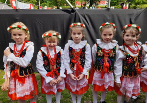 Pięć dziewczynek z grupy "Słoneczka" stoi obok sceny w strojach krakowskich.