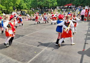 Dzieci w strojach krakowskich tańczą na scenie Krakowiaka.
