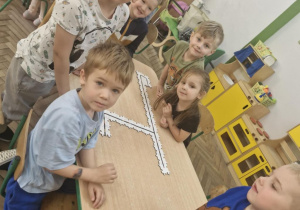 Dzieci siedzą przy stoliku, na którym rozłożyły z puzzli ścieżkę dla Ozobotów.