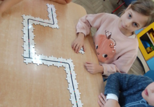 Grupa dzieci przy stolikach układa drogę - puzzle do Ozobotów.