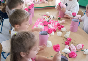 Grupka dzieci tworzy bukiety z kwiatów mydlanych.