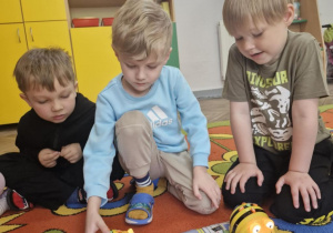 Olek programuje swojego BeeBota, obok siedzą Tymuś i Wojtuś.