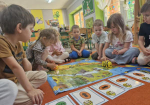 Dzieci siedzą wokół mapy do kodowania i programują BeeBoty.