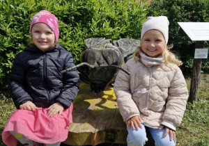 Klara i Alicja pozują do zdjęcia przy rzeźbie pszczoły.